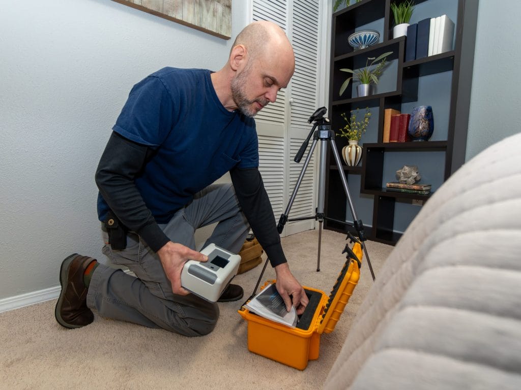 Technician conducting a radon testing service inside a home using professional equipment
