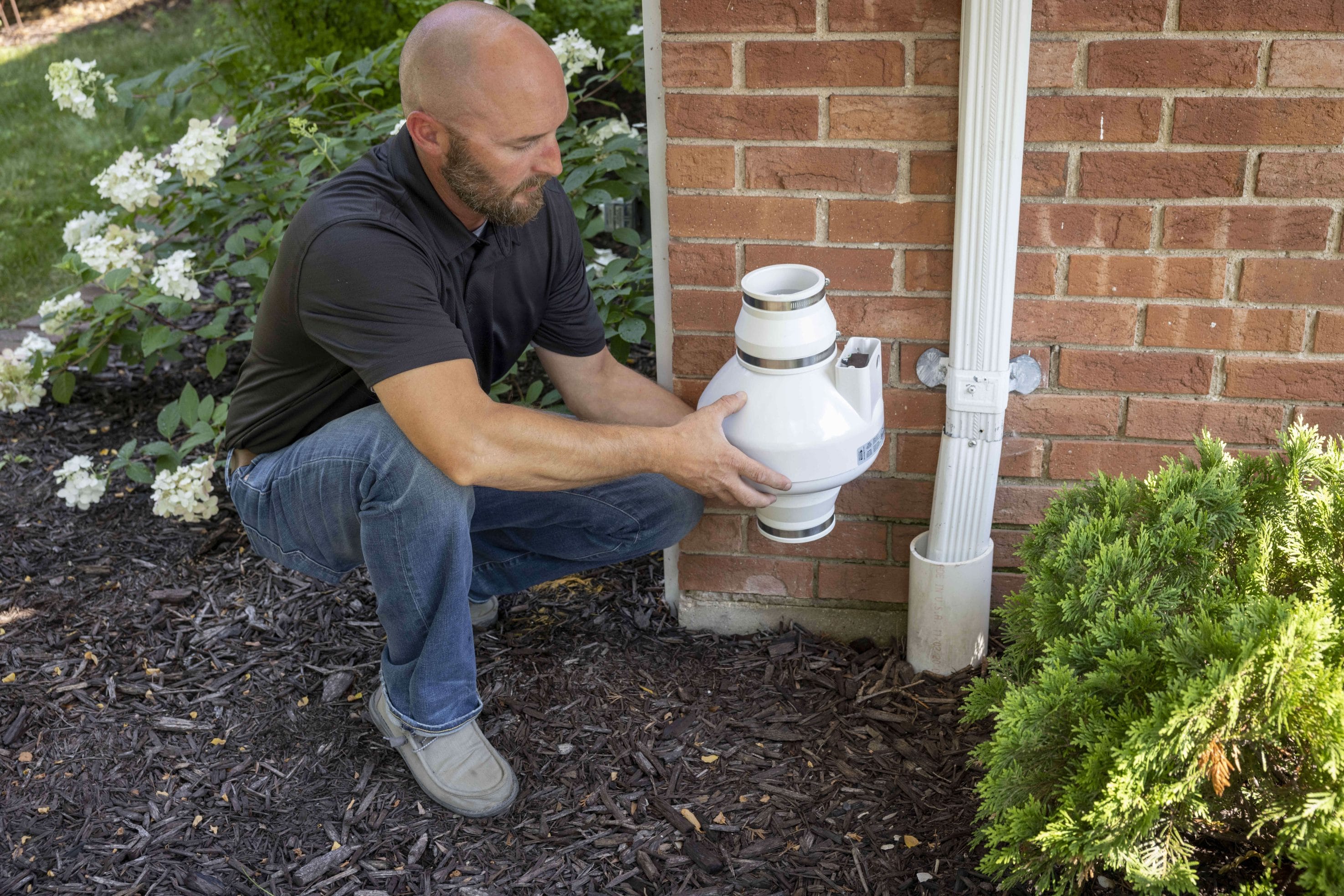 Radon technician installing radon mitigation system outdoors
